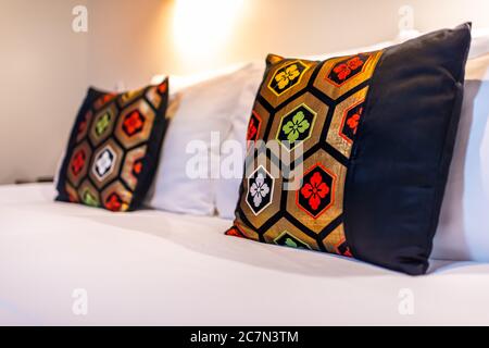 Modern contemporary Japanese house ryokan hotel bedroom room with two colorful red green black pillows on white clean made bed Stock Photo