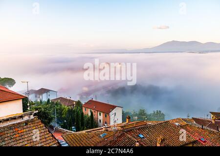 Sunrise fog mist at old historic medieval town of Chiusi, Tuscany in Italy with landscape rolling hills view and colorful red roof buildings illuminat Stock Photo