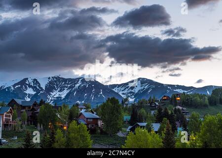 Cityscape of Mount Crested Butte village, small mountain town in Colorado in summer with dark morning night clouds and chalet wooden houses on hills w Stock Photo
