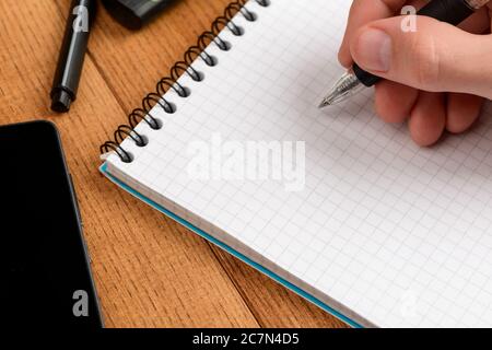 Writing in a notepad. Close up on a male hand leaving a note Stock Photo