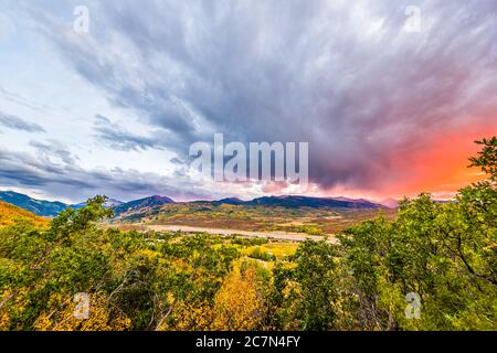 Aspen, Colorado rocky mountains colorful sunset orange red light in sky clouds wide angle high angle aerial view with storm clouds and foreground of p Stock Photo