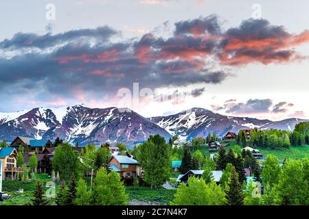 Cityscape of Crested Butte village small mountain town in Colorado in summer with dark morning sunrise clouds and chalet wooden houses on hills with g Stock Photo