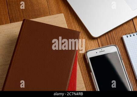 Books, phone and laptop on wooden table Stock Photo