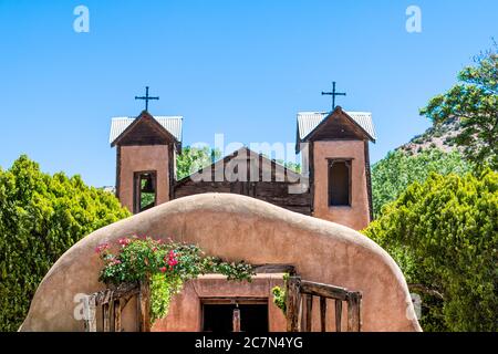 Famous historic El Santuario de Chimayo sanctuary church in the United States with entrance gate closeup of flowers in summer Stock Photo