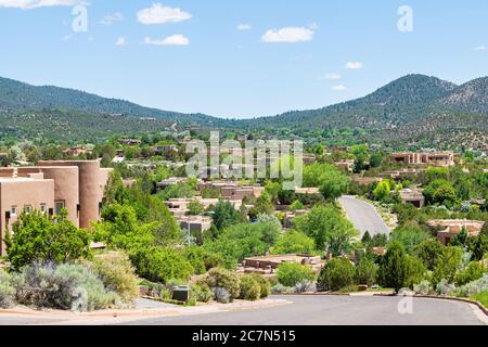 Cityscape view in Santa Fe, New Mexico mountains of road street through community neighborhood with green plants summer and adobe traditional houses Stock Photo