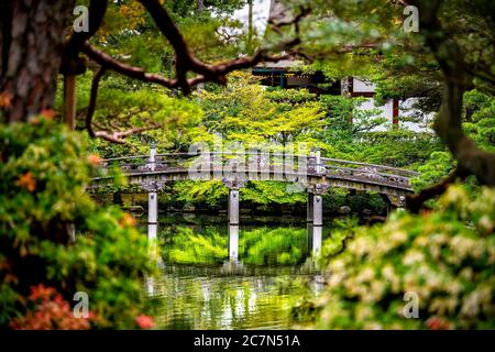 Kyoto, Japan framing view of green spring garden in Imperial Palace with water reflection and stone bridge on peaceful lake pond Stock Photo