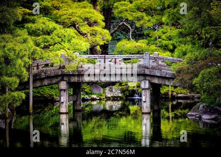 Kyoto, Japan closeup view of green spring garden in Imperial Palace with water reflection and stone bridge on lake pond Stock Photo