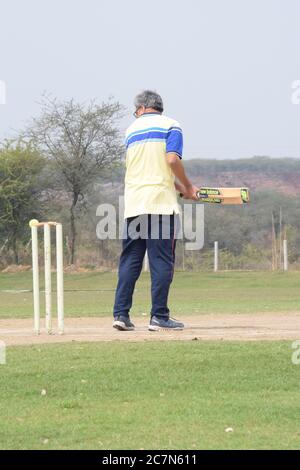 Full length of cricketer playing on field during sunny day, Cricketer on the field in action, Players playing cricket match at field during the day ti Stock Photo