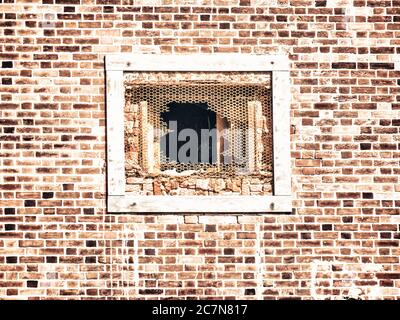 Spider web on a metallic broken and aged window of a brick building Stock Photo