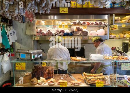 Rome/Italy - 09.10.2017; A typical traditional Italian deli store with two men preparing sandwiches with fresh ingredients. Specialties are displayed. Stock Photo