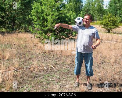 A man plays a soccer ball on a forest lawn. Stock Photo