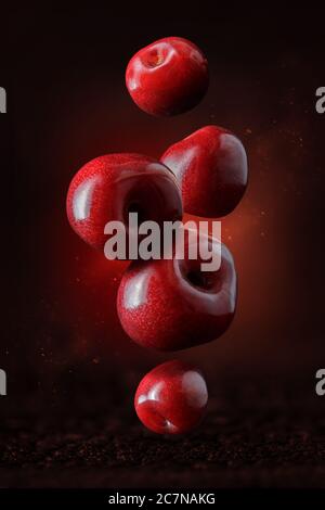 Flying or levitated cherries on a dark background with steam or water particles Stock Photo