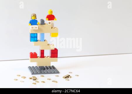 Winnipeg, Manitoba / Canada - July 10, 2020: Lego Mini Figure Man and Woman in the top of a Dollar Sign. Lego is a Popular Line Toys Manufactured by t Stock Photo