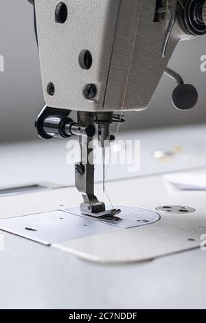 Vertical shot of a white sewing machine on a white table Stock Photo