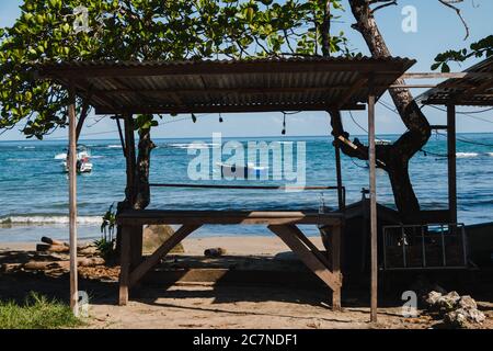 A wooden table on the sand in front of a beach overlooking the Caribbean Sea in Puerto Viejo, Costa Rica Stock Photo