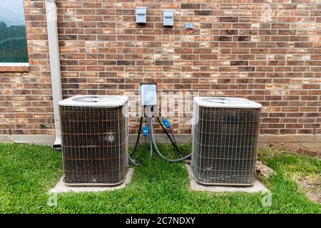 Two older air conditioner systems next to brick home with copy space. Stock Photo