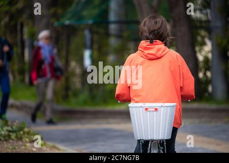 Kyoto, Japan - April 17, 2019: Japanese person back on bicycle riding bike basket on street candid city life road near station Stock Photo