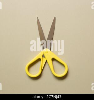 Yellow scissors isolated on beige background. top view Stock Photo