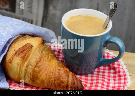 Picture of a croissant with a cup of coffee on a checkered cloth Stock Photo