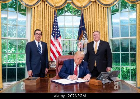 Washington, United States Of America. 14th July, 2020. President Donald J. Trump, joined by Treasury Secretary Steven Mnuchin and Secretary of State Mike Pompeo, signs the unanimously approved H.R. 7440, the 'Hong Kong Autonomy Act' Tuesday, July 14, 2020, in the Oval Office of the White House People: President Donald Trump, Steven Mnuchin, Mike Pompeo Credit: Storms Media Group/Alamy Live News Stock Photo