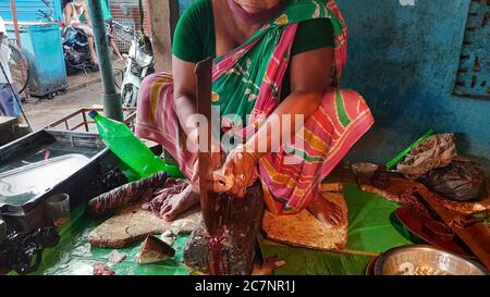 Fish stall with a woman slicing fish for customers at a local city market at Kolkata Stock Photo