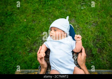 A little baby is resting in his mothers lap outdoors Stock Photo