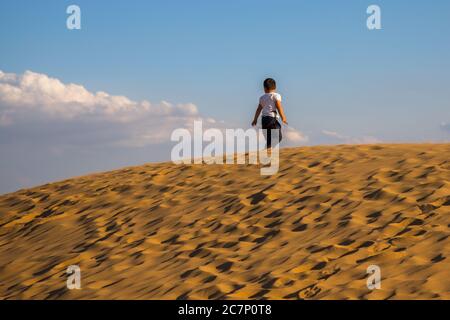 a boy having good time on top of sun dunes in XiangshaWan, or Singing sand Bay, in hobq or kubuqi desert, Inner Mongolia, China Stock Photo