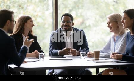 Five multiethnic company staff gather together talking planning future project Stock Photo