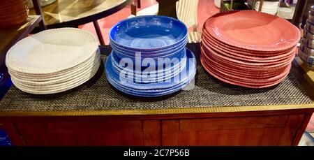 High angle shot of different colored plate and bowl stacks on a table at a store Stock Photo