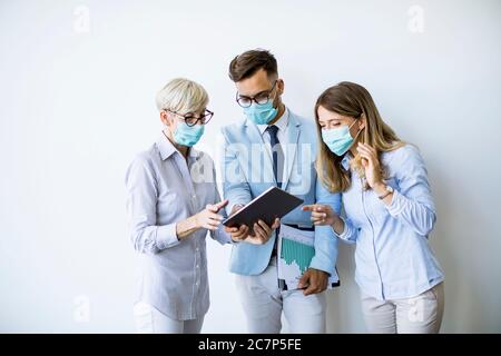 Business partners standing and looking at business results in the office while wearing face masks sa an virus protection Stock Photo