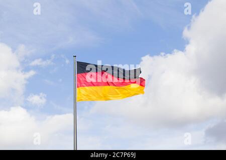 Germany national flag, red, black and yellow colors on the blue sky background. Stock Photo