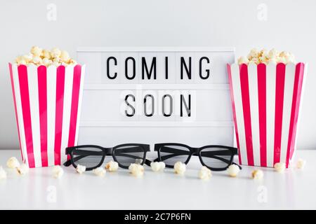 cinema concept - red striped boxes with popcorn, 3d glasses and light box with "coming soon" text Stock Photo