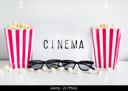 cinema concept - red striped boxes with popcorn, 3d glasses and light box with cinema word Stock Photo