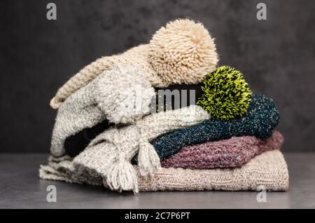 A stack of folded knitted winter scarves and hats. Season of warm clothes. Time to keep warm. Closeup Stock Photo