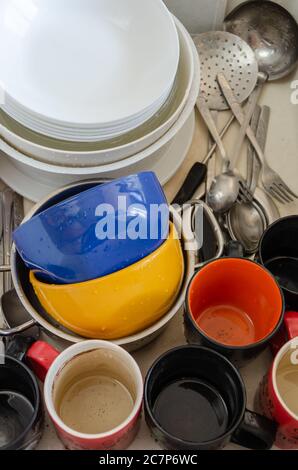Dirty dishes in a ceramic kitchen sink. Unwashed plates, mugs and cutlery. Top view. Closeup Stock Photo