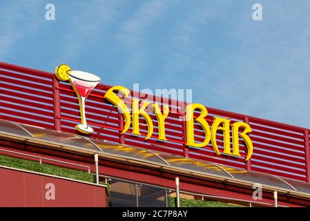 Sky Bar yellow neon lights sign for rooftop bar on hotel facade in daylight Stock Photo