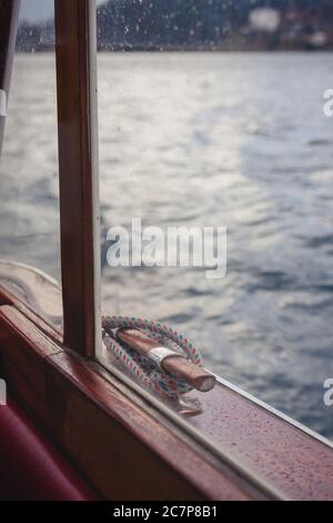 Mooring cleat detail on retro wooden boat window on atmospheric rainy day Stock Photo