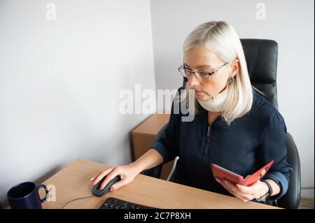 Mature woman in pain wearing a surgical collar on her neck ,working on computer in business office Stock Photo