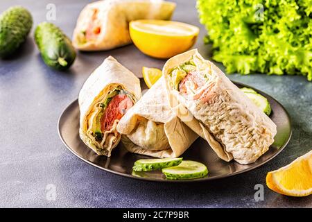Wrapped sandwich with salmon, lettuce, cucumber and cream cheese, selective focus. Stock Photo