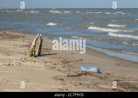 Plastic bottle washed ashore by the waves. Massive plastic pollution on the Black Sea coastline in Danube Biosphere Reserve. Plastic garbage environmental pollution problem. Plastic and other garbage from all over Europe is washed out by the Danube river into the Black Sea. Stock Photo