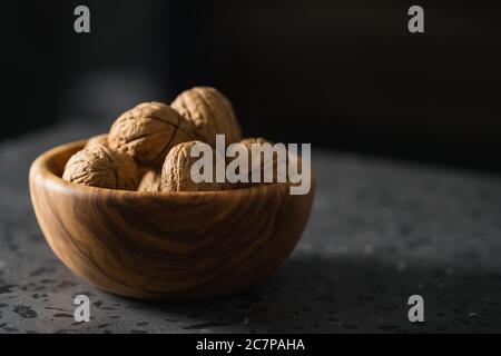 inshell walnuts in olive wood bowl on terrazzo countertop Stock Photo