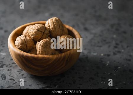 inshell walnuts in olive wood bowl on terrazzo countertop Stock Photo