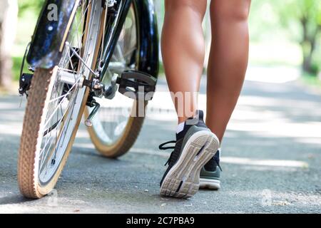 Legs of young fit woman riding bicycle in a city park Stock Photo