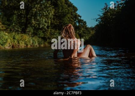 Beautiful woman skinny dipping and wild swimming in river Stock Photo