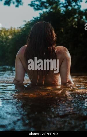 Beautiful woman skinny dipping and wild swimming in river Stock Photo