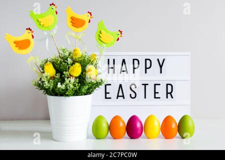 Vintage lightbox with happy Easter greetings, flower pot and colorful painted eggs Stock Photo