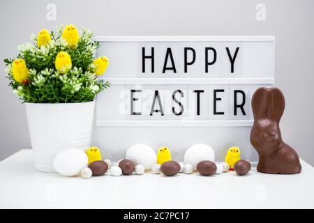 Close up of vintage lightbox with happy Easter greetings, Easter eggs, sweets and decorations on the table Stock Photo