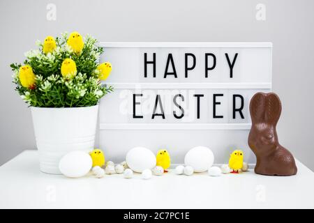 Close up of vintage lightbox with happy Easter greetings, chocolate bunny, Easter eggs and decorations Stock Photo