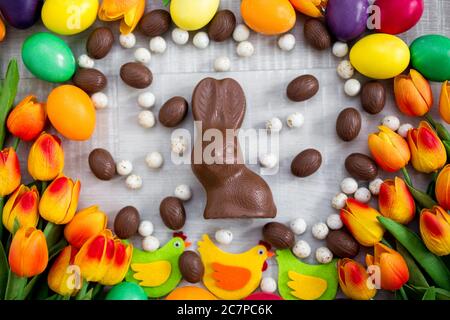 Easter background - close up of colorful eggs, decorations, tulips, chocolate bunny and sweets Stock Photo