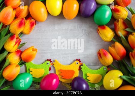 Easter frame background - close up of colorful eggs, decorative chicks and tulip flowers Stock Photo